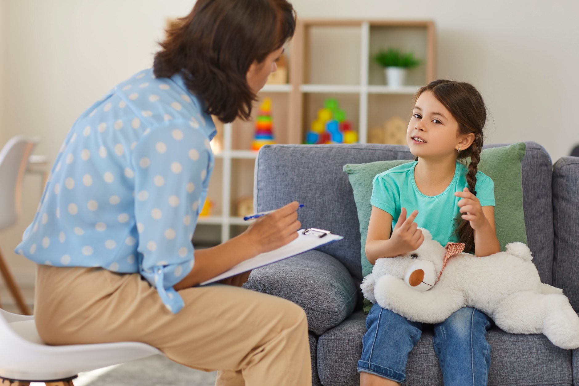 Happy Little Girl Telling Story to Child Psychologist during Therapy Session in Cozy Modern Office